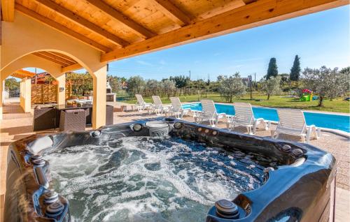 wanna z hydromasażem na patio z krzesłami i basenem w obiekcie Nice Home In Marcana With Sauna w mieście Muntić