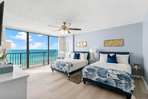 a bedroom with two beds and a balcony with the ocean at Sandpiper Beacon Beach Resort in Panama City Beach