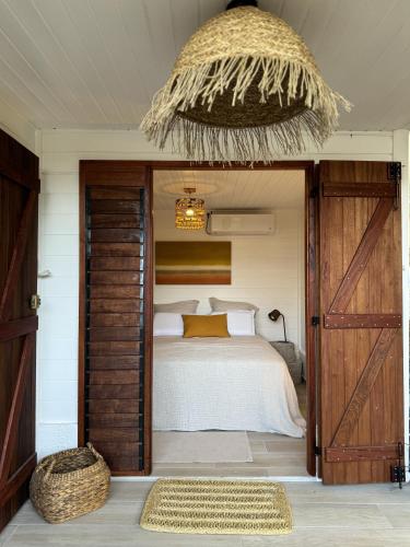 a bedroom with a bed with a wooden door and a basket at Les Cabanes cosy à 2 pas du lagon - charme et confort in Le François