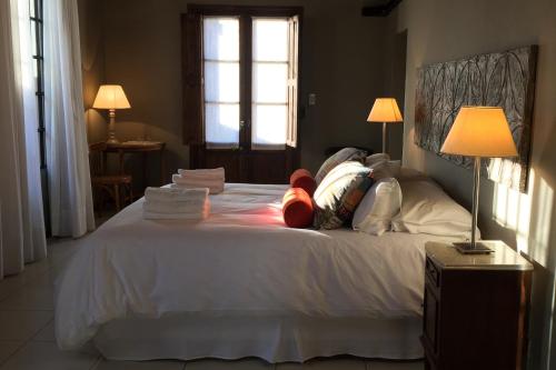 a bedroom with a white bed with pillows and a window at Posada Verde Oliva in Maipú