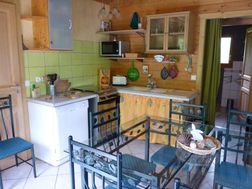 a kitchen with a stove and a sink and chairs at Les Myrtilles in Le Bonhomme