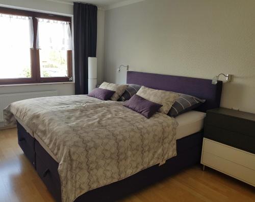 a bedroom with a large bed with purple pillows at Schöne 120-qm-Ferienwohnung - Sonnenterrasse - Stadtgrenze Lübeck in Stockelsdorf