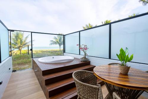 a bathroom with a tub and a table and chairs at Alta Garden Housi João Pessoa by Carpediem in João Pessoa