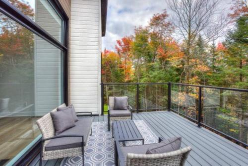 a screened in porch with chairs and a table at Chalet Allegria Tremblant in La Conception