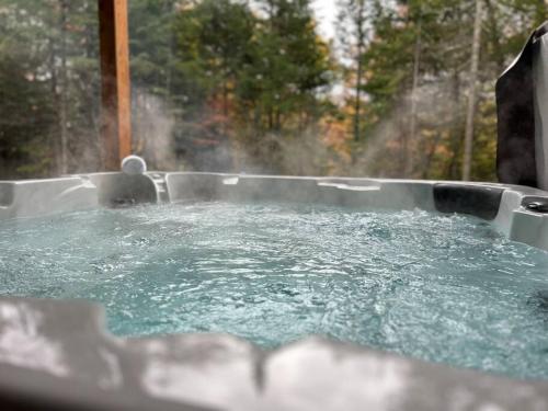 a hot tub filled with water in front of a window at Chalet Allegria Tremblant in La Conception