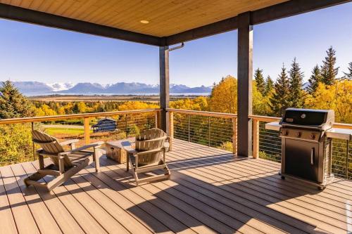 a screened in porch with a grill and chairs on it at Inlet View Home in Homer