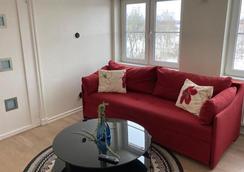 a living room with a red couch and a table at Déus Longstay in Rosersberg