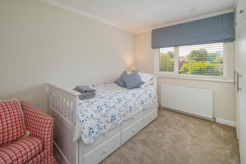 a white bedroom with a crib and a window at Meadow Drive in Bembridge