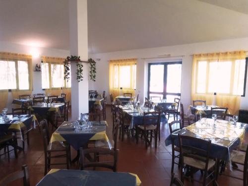 ein Esszimmer mit Tischen, Stühlen und Fenstern in der Unterkunft Nuraghe Ruiu Piazzole campeggio Blue Holiday in Norbello