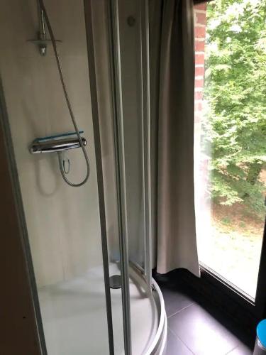 a glass shower in a bathroom with a window at dar zaina in Blaimont