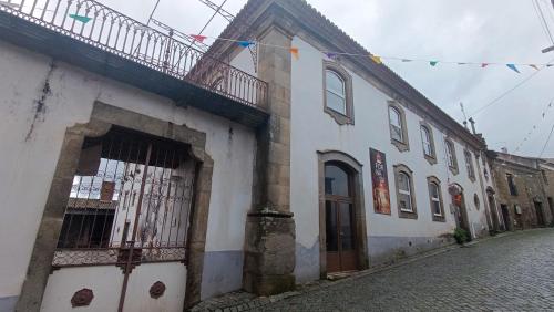 a white building with a gate on a street at Orion Guesthouse Telhado in Fundão