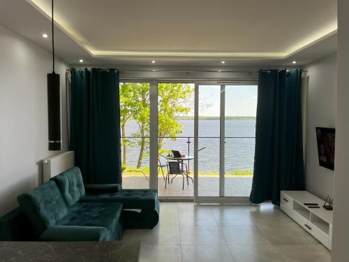 a living room with a couch and a view of the water at Apartament Lake House Zegrze in Zegrze