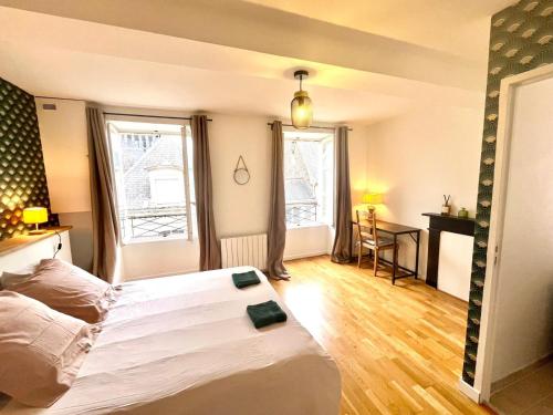 a bedroom with a large white bed and a desk at Petit appartement centre historique Laval in Laval