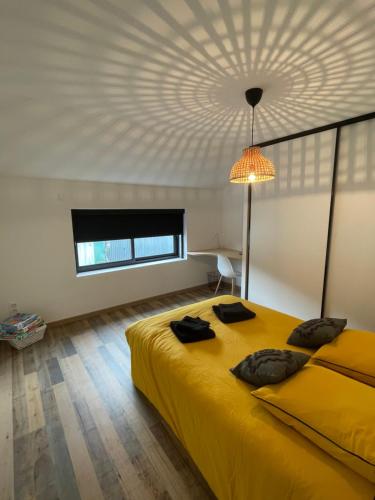 - une chambre avec un grand lit jaune et un plafond dans l'établissement Appartement loft, à Châteaubriant