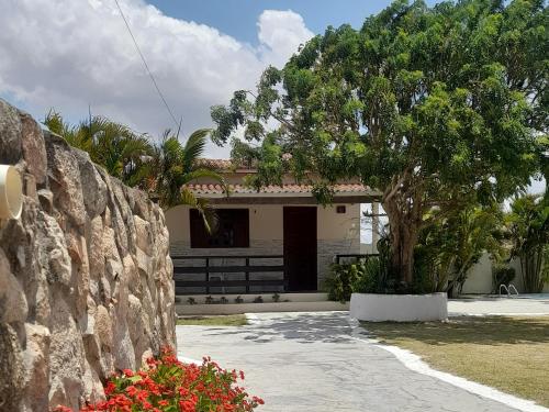 a house with a stone wall and a tree at Pousada Vale Encantado in Serra de São Bento