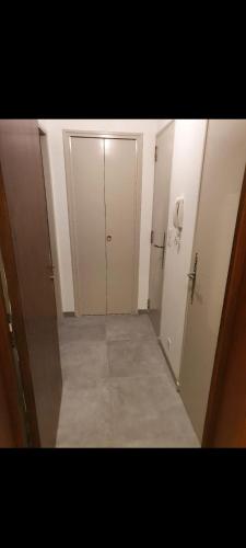 un couloir vide avec deux portes blanches et un téléphone dans l'établissement Residence le Cézanne vue panoramique climatisée, à Gréoux-les-Bains