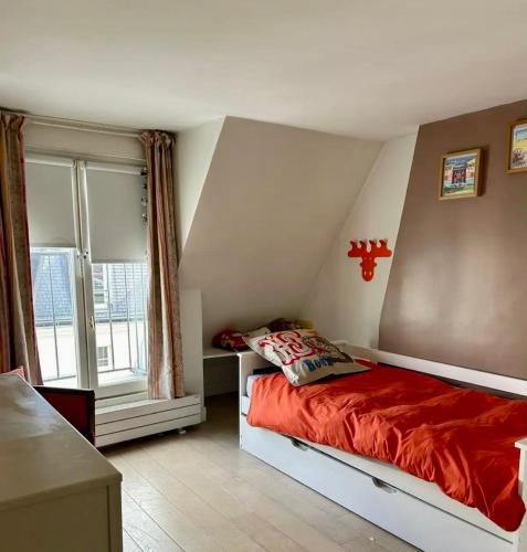une chambre avec un lit avec une couette rouge et une fenêtre dans l'établissement Paris Montorgueil, à Paris