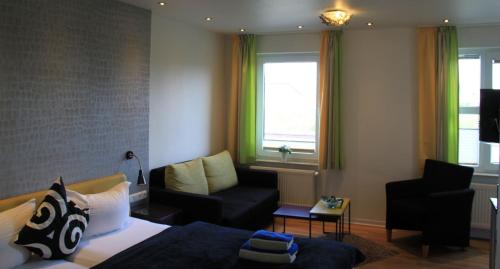 a bedroom with a bed and a couch and a window at Strandhotel Achtert Diek in Langeoog