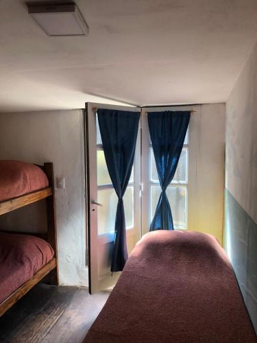 a bedroom with a bed and a window with blue curtains at Hostel Playa Pura Vida mdq in Mar del Plata