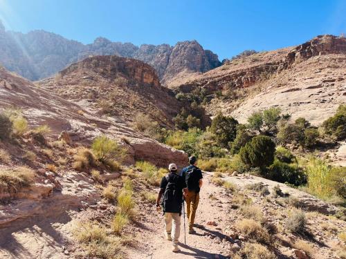 two people walking down a dirt trail in a canyon at Bedouin outdoors Camp wild in Dana