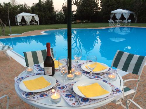 einen Tisch mit einer Flasche Wein und Gläsern neben einem Pool in der Unterkunft Borgo Dei Conti Della Torre in Morsano al Tagliano