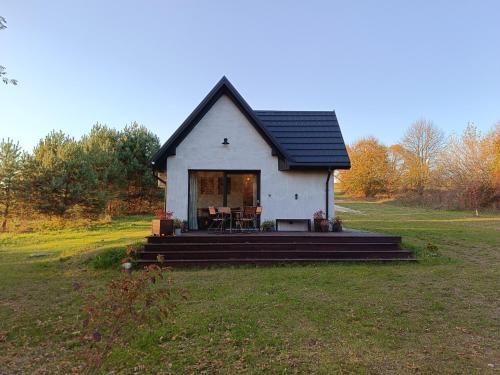 a small white house with a black roof on a field at Domki na polance in Horyniec Zdrój