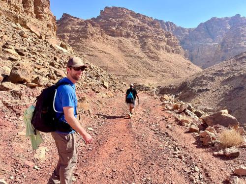 two people walking down a dirt road in the desert at Bedouin outdoors Camp wild in Dana