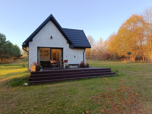 a small white house with a porch in a field at Domki na polance in Horyniec Zdrój