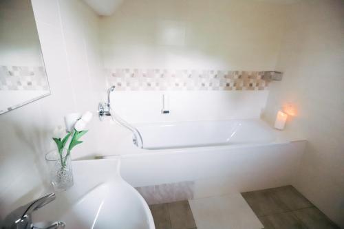 a white bathroom with a tub and a vase of flowers at Amantis Vital Sport Hotel in Desná