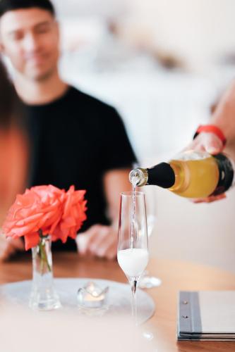a person pouring a bottle of wine into a wine glass at Amantis Vital Sport Hotel in Desná
