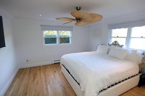 a white bedroom with a bed and a ceiling fan at Modern Comfy Retreat Patio Outdoor Salt Hot Tub in East Hampton