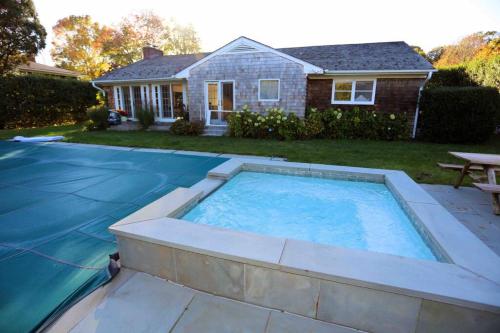 a large swimming pool in the yard of a house at Modern Comfy Retreat Patio Outdoor Salt Hot Tub in East Hampton