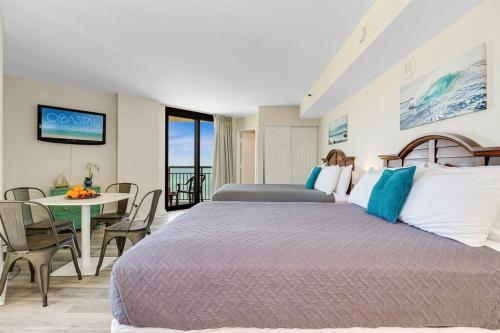 a bedroom with a large bed and a table with chairs at Supreme Oceanfront Studio, Dogs OK! 1126 in Myrtle Beach
