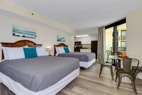 a hotel room with two beds and a table and chairs at Supreme Oceanfront Studio, Dogs OK! 1126 in Myrtle Beach