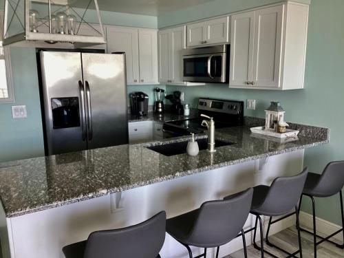 a kitchen with white cabinets and a black refrigerator at Ocean Walk Resort - Striking Ocean Front View in Daytona Beach