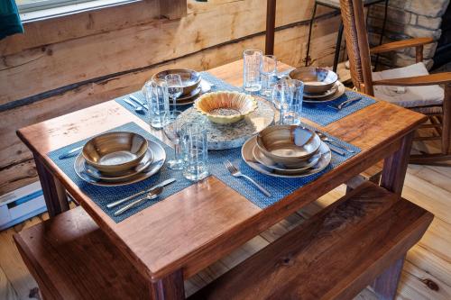 a wooden table with plates and glasses on it at Gorgeous Log Cabin - Wineries, Dan River, Hiking in Meadows of Dan
