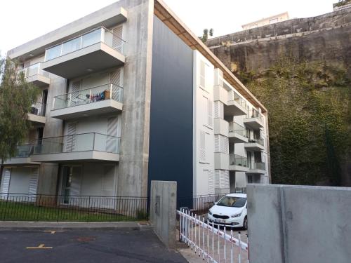 an apartment building with a car parked in front of it at Costa Lodges, Funchal or Santa Cruz Madeira, shared room in Santa Cruz