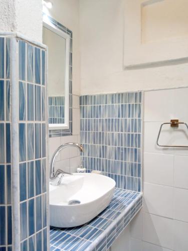 a bathroom with a white sink and blue tiles at La Casa Rossa in Stintino