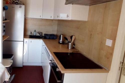 une cuisine avec des armoires blanches et un comptoir en bois dans l'établissement Appartement à 5mn de la mer et du Village de Noël - draps et serviettes non fournis, au Barcarès