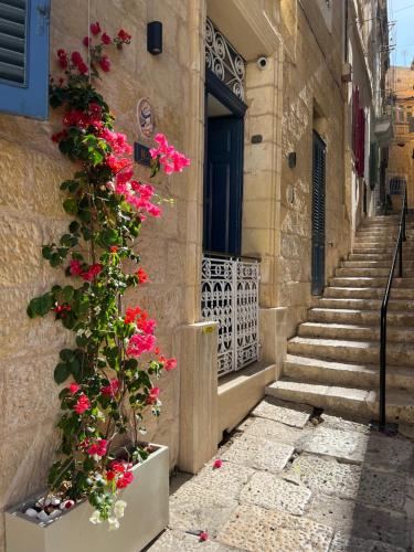 un bâtiment avec des fleurs roses sur le côté dans l'établissement Moon Malta Boutique Stay with Rooftop Pool & Sea Views of Valletta, Grand Harbour & Three Cities, à Cospicua