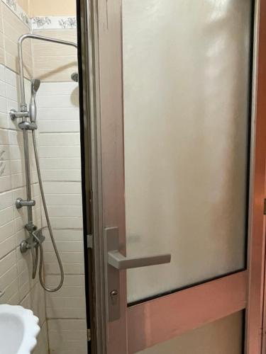 a shower door in a bathroom with a sink at Garden Room in Nzamata