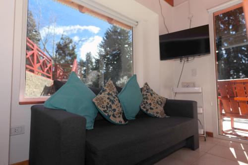 a couch with pillows sitting in a living room with a window at Amutuy Bariloche in San Carlos de Bariloche