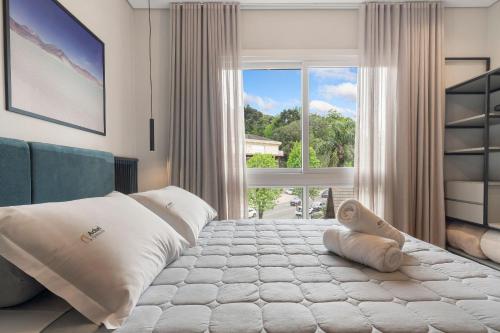 a bedroom with a large bed with a large window at Res. Tribeca 350m Rua Coberta by Achei Gramado in Gramado