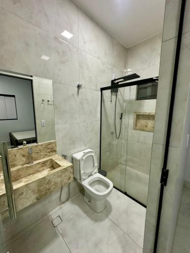 a bathroom with a toilet and a shower and a sink at Casa ARUANÃ 6 SUITES in Aruanã