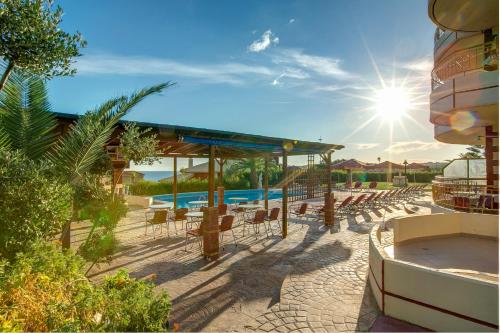 a resort with a pool and chairs and the sun at Marina-Anna Studios in Trapezaki