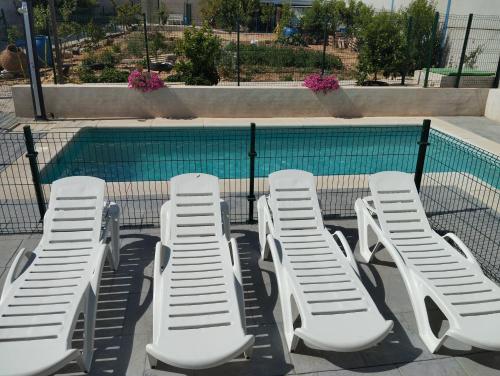 un gruppo di sedie a sdraio bianche accanto alla piscina di El capricho de Diego a La Puebla de Montalbán