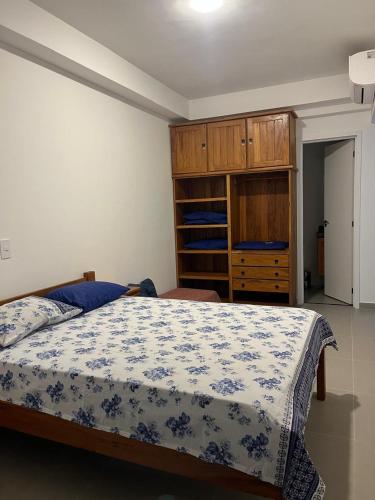 a bedroom with a blue and white bed and wooden cabinets at Apto de ferias em Bertioga Maitinga in Bertioga