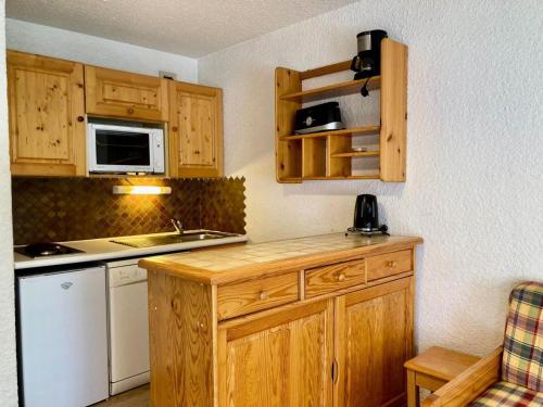 Elle comprend une petite cuisine avec des placards en bois et un évier. dans l'établissement Résidence Meijotel - Studio résidence Meijotel MAE-9421, à Vénosc