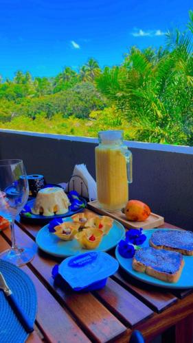 a table with plates of food and a jar of orange juice at Pousada Mon Gâté in Japaratinga