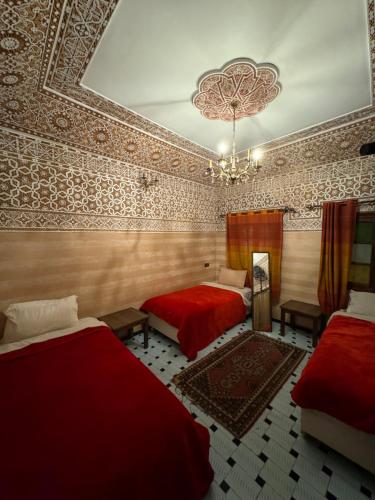 a bedroom with two beds and a chandelier at Riad Dar Essassi 23 in Marrakech